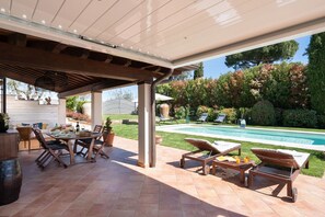Eine Außenpatio mit Pool, Liegestühlen und Essbereich inklusive Tisch und Stühlen.