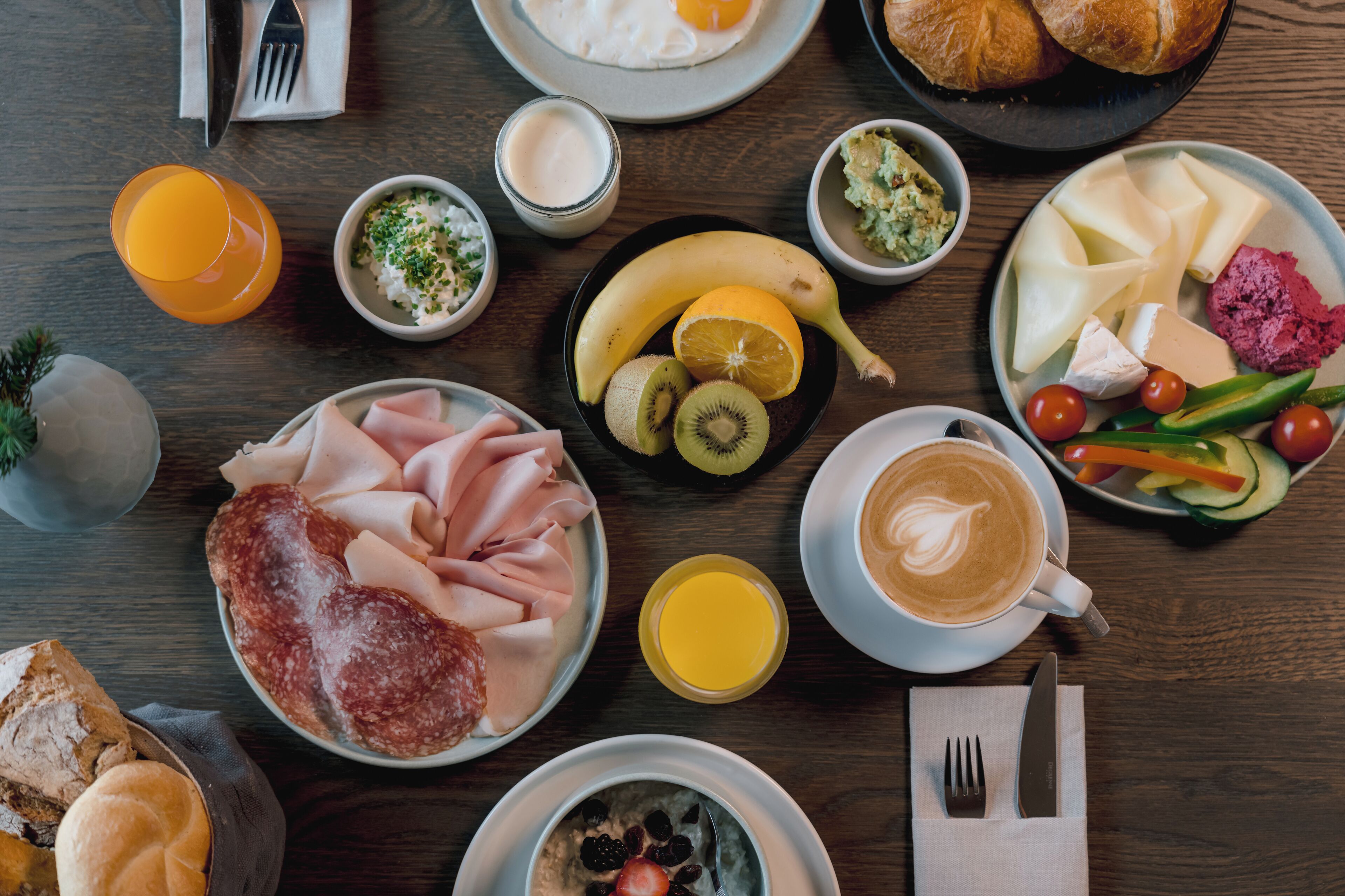 A breakfast spread with various foods and drinks on a wooden table.
