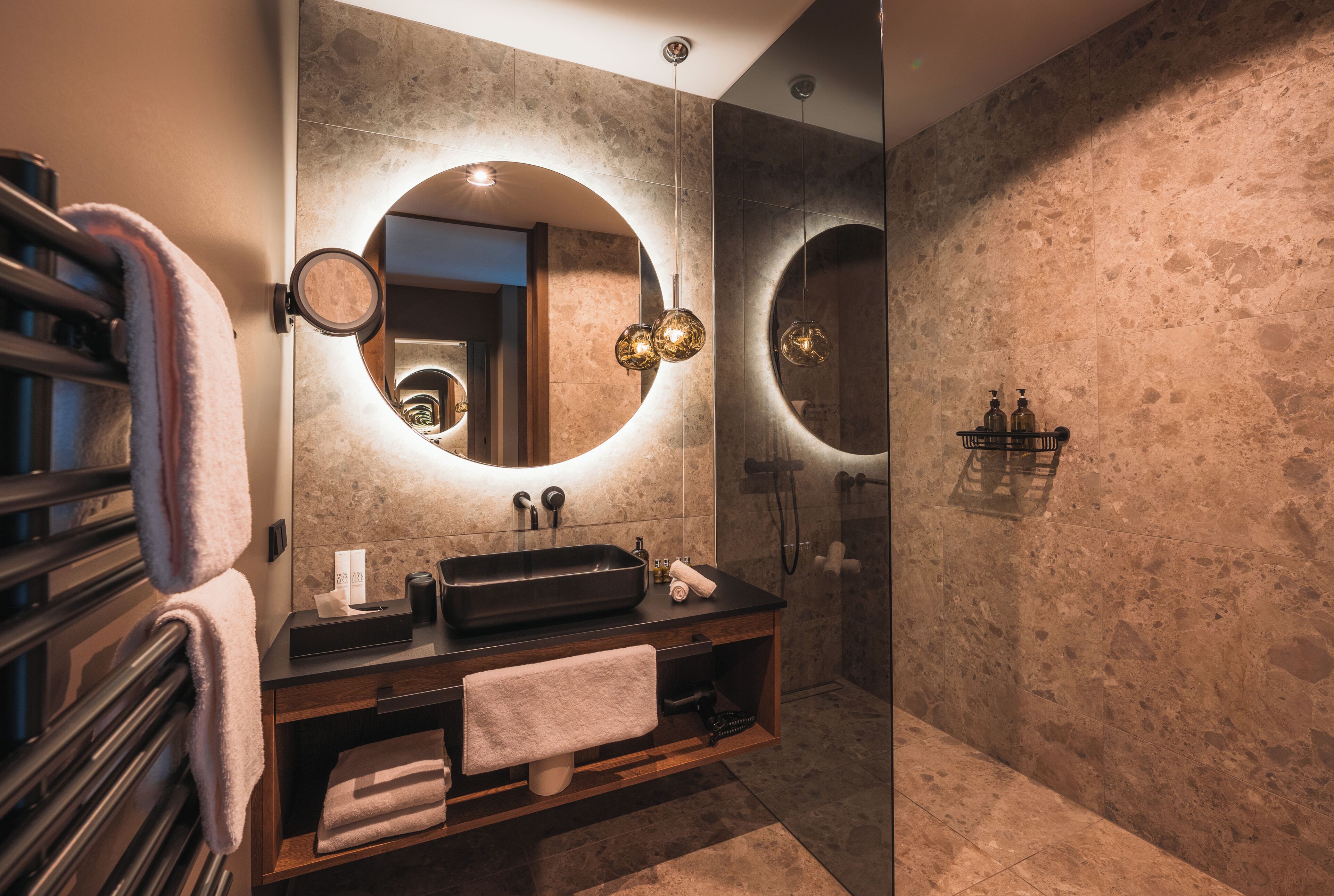 A modern bathroom with a large mirror, a sink, and a shower.