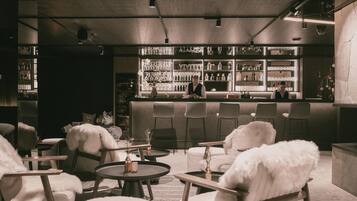 A bar area with a bartender, round tables, and chairs.