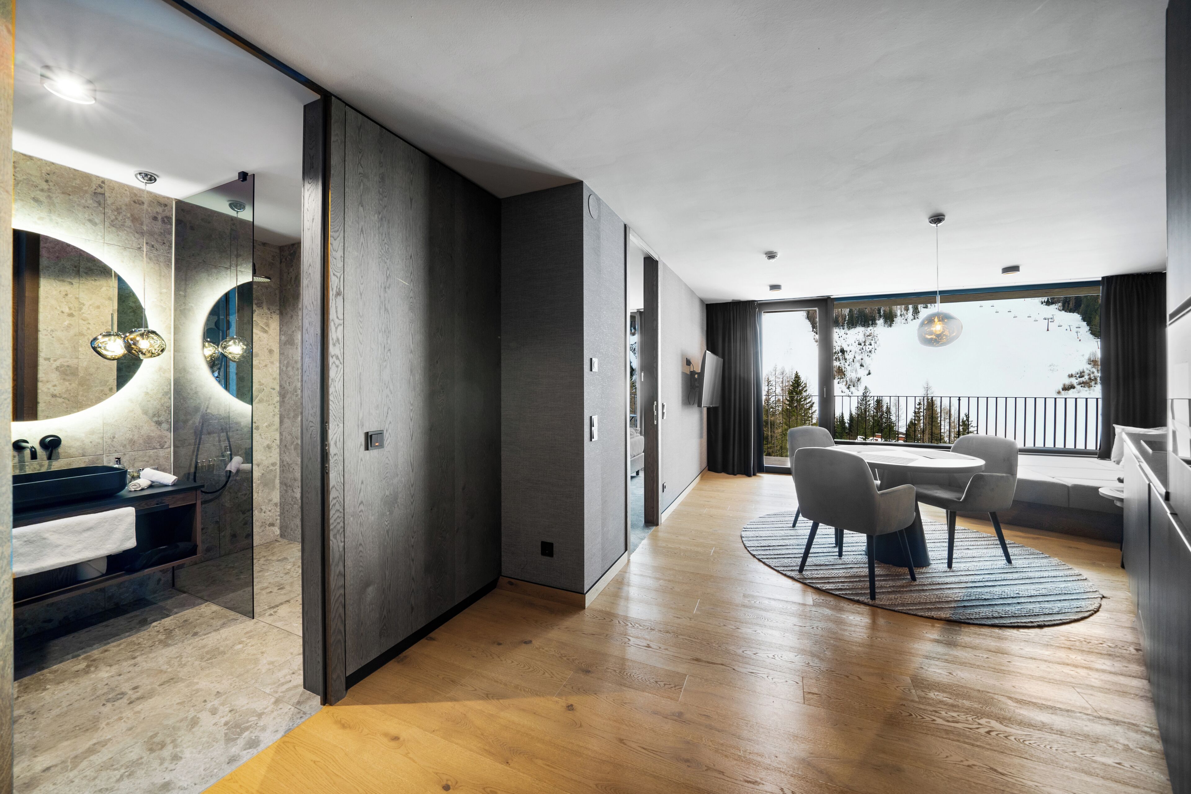 Un intérieur moderne comprenant une salle de bain, un coin repas et une vue sur un paysage enneigé.