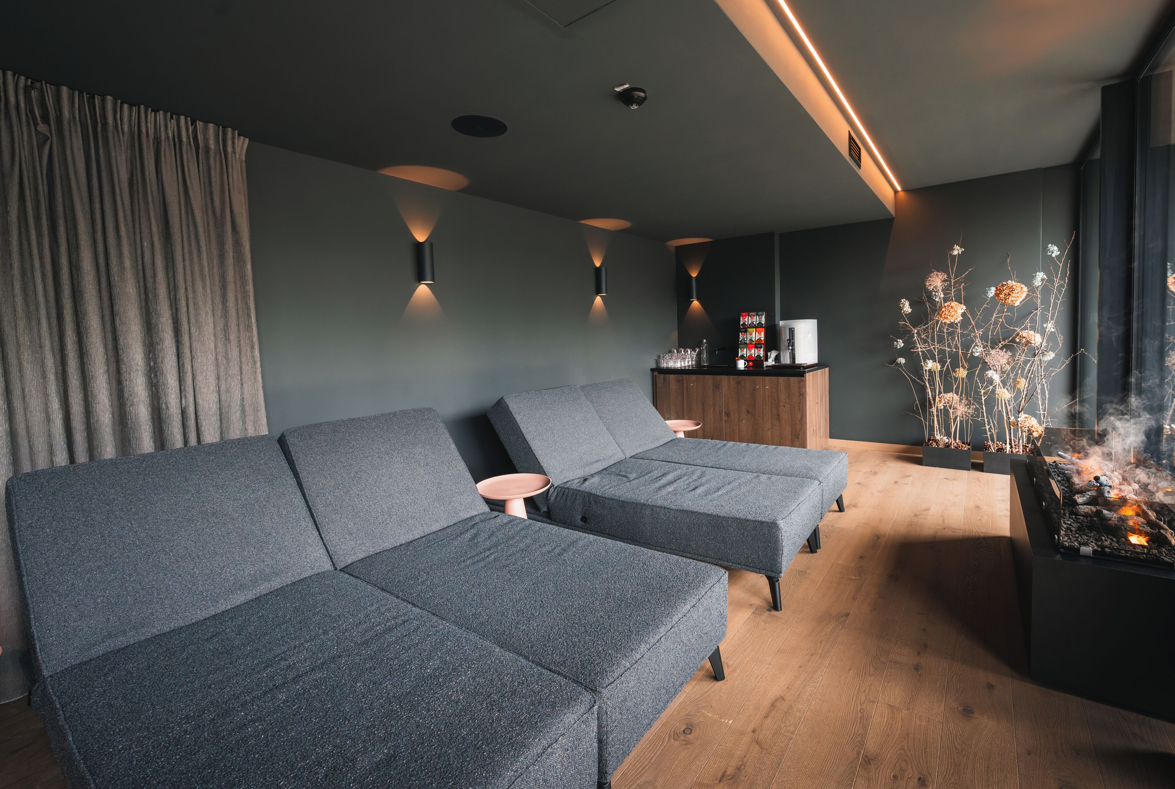 Een moderne woonkamer met een hoekbank, een bijzettafeltje en een open haard.