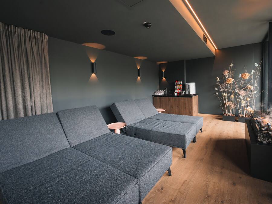 Een moderne woonkamer met een hoekbank, een bijzettafeltje en een open haard.