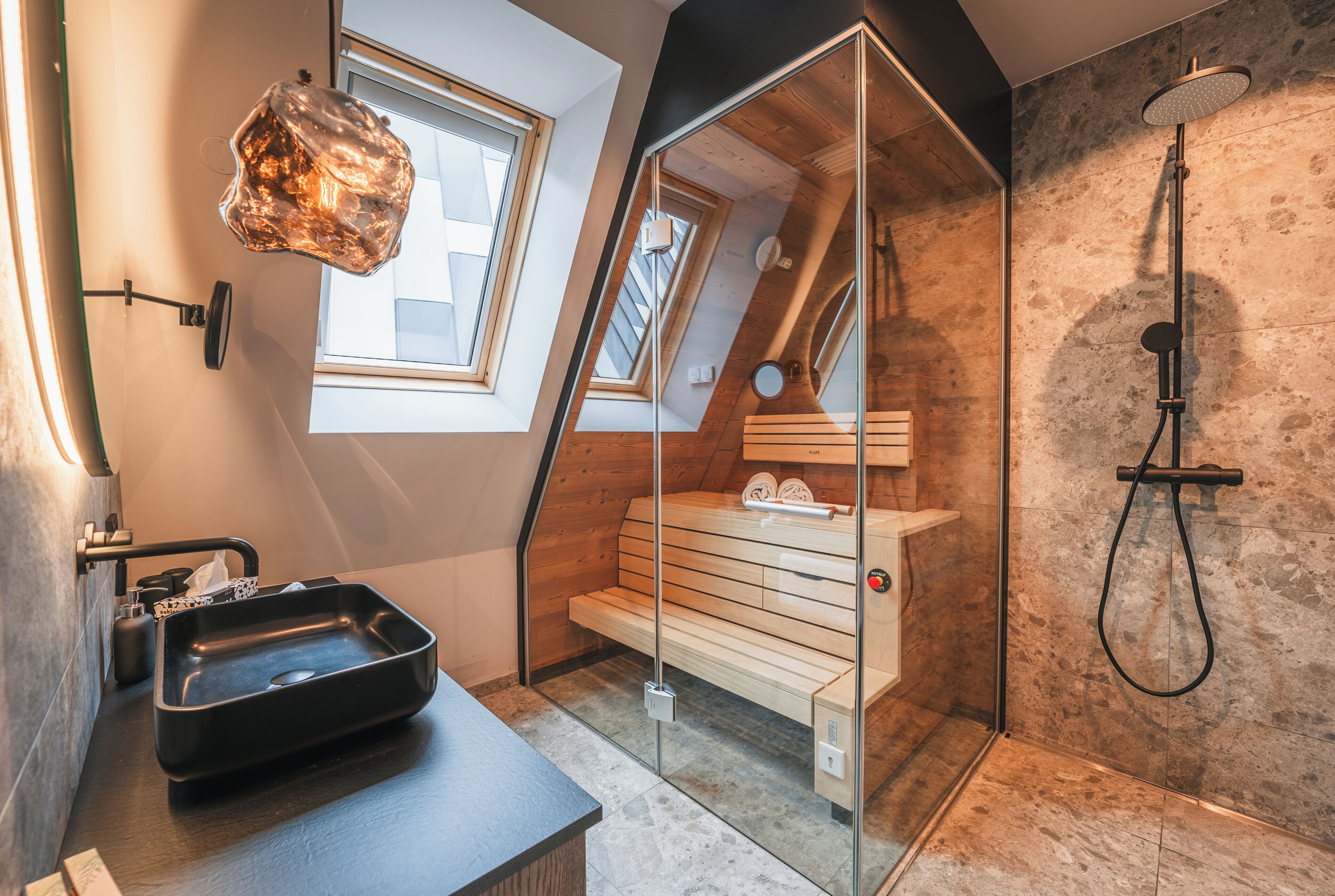 A modern bathroom with a skylight, a shower, and a wooden bench.