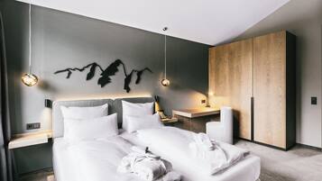 Una habitación de hotel moderna con una cama grande, un armario de madera, una obra de arte colgada en la pared y lámparas de noche.