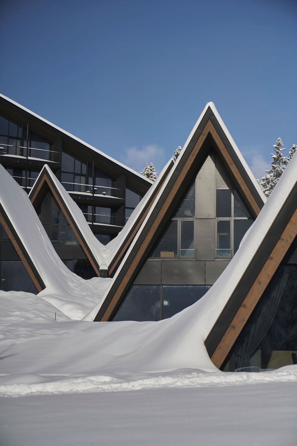 A modern building with angular, triangular roof structures and large windows.