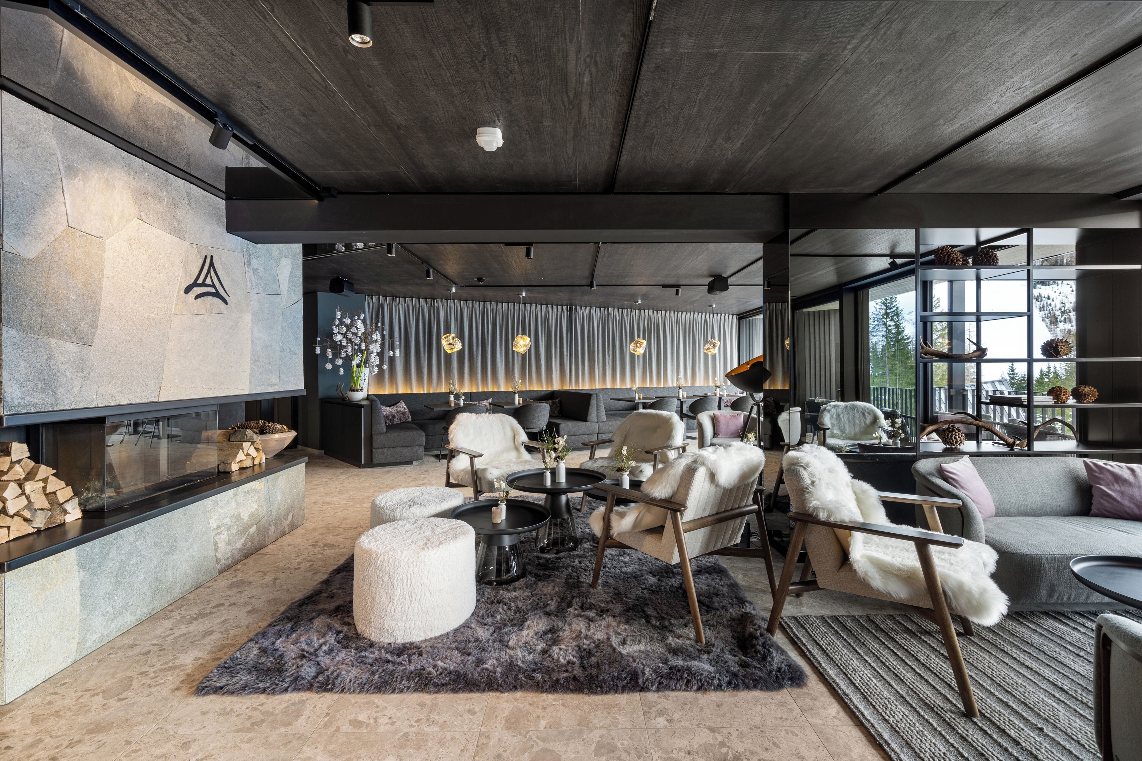 A modern living room with a fireplace, seating area, and large windows.