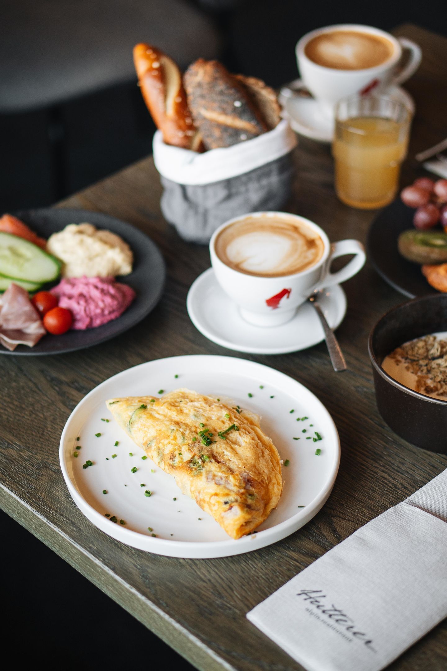 A breakfast setting with croissants, coffee, and a variety of spreads on a wooden table.