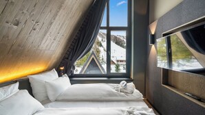 Un dormitorio con un ventanal grande, una cama y un televisor.