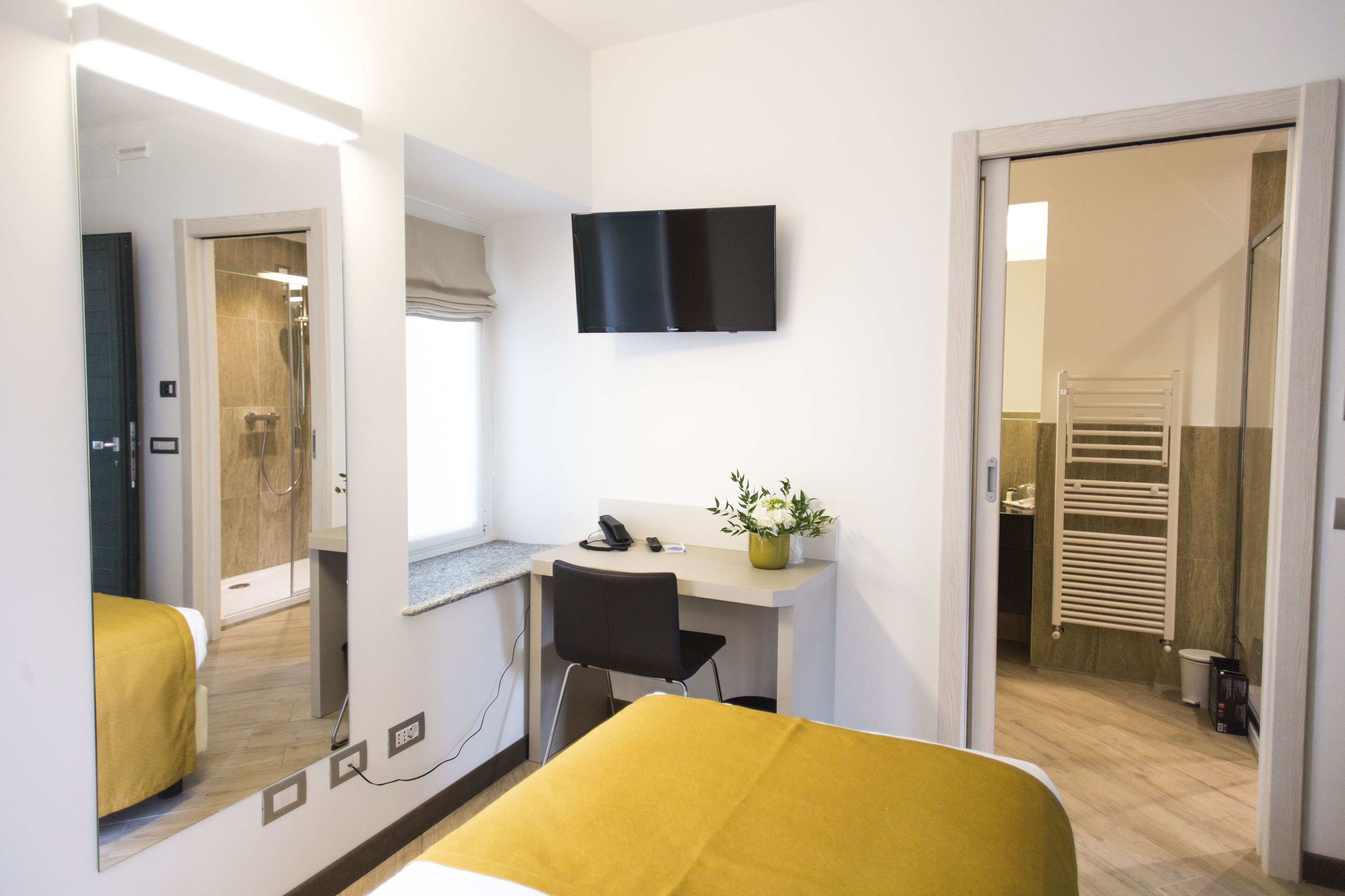 Une chambre d’hôtel avec un lit, un bureau et une chaise, une télévision et une salle de bain visible à travers une porte ouverte.