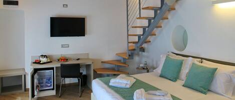 A hotel room with a bed, a desk with a computer, a TV, and a staircase.