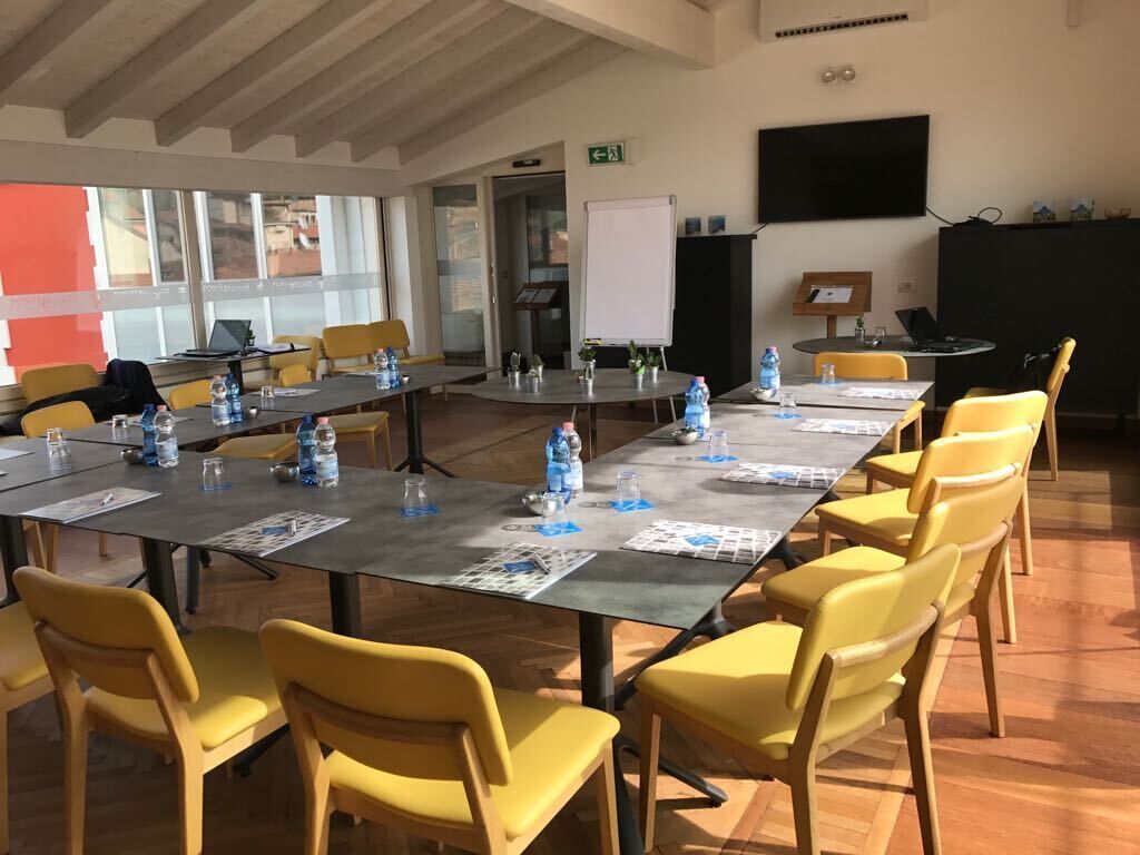 A conference room with a long table, yellow chairs, water bottles, and a whiteboard.