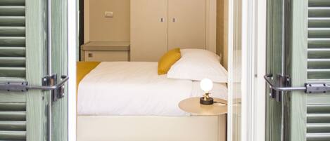 A hotel room with a bed, bedside table, and a wardrobe.