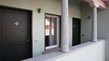 A building entrance with a dark wooden door, a window, and a stone column.
