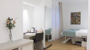 Una habitación de hotel moderna con escritorio, silla y cama con manta color turquesa.