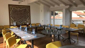 A conference room with multiple tables and yellow chairs, equipped with water bottles and papers.