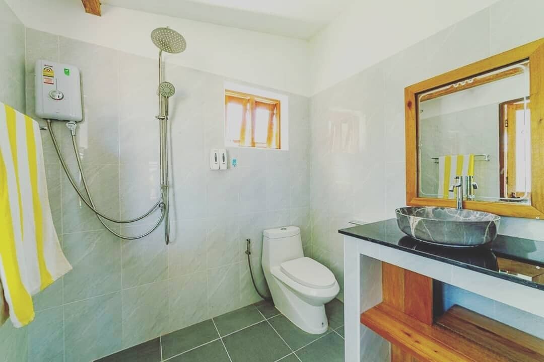 Een badkamer met douche, toilet en wastafel met spiegel.