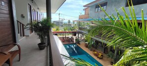A pool area with a view of a building, potted plants, and outdoor furniture.