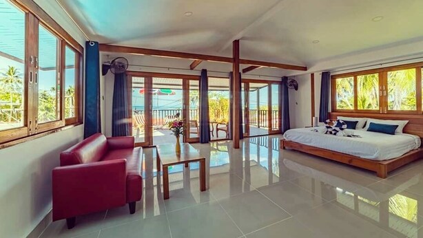 Una habitación amplia con una cama grande, un sofá rojo y una mesa de comedor.