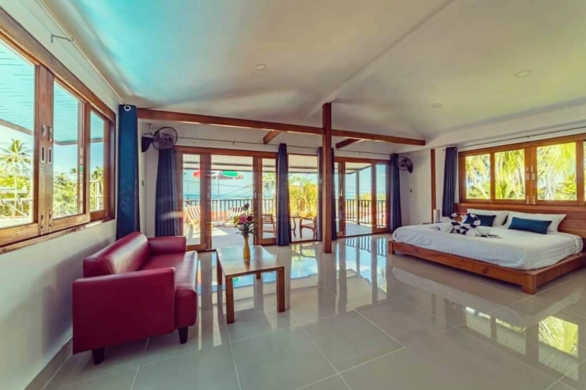 Una habitación amplia con una cama grande, un sofá rojo y una mesa de comedor.