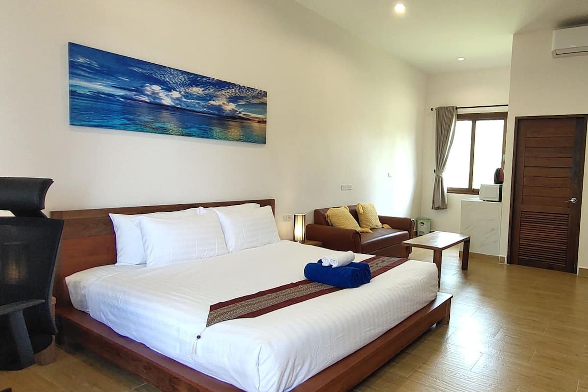 Una habitación de hotel con una cama grande, un escritorio, una silla, un televisor y un cuadro en la pared.