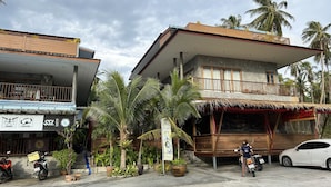 Un edificio de dos pisos con balcón, rodeado de palmeras.