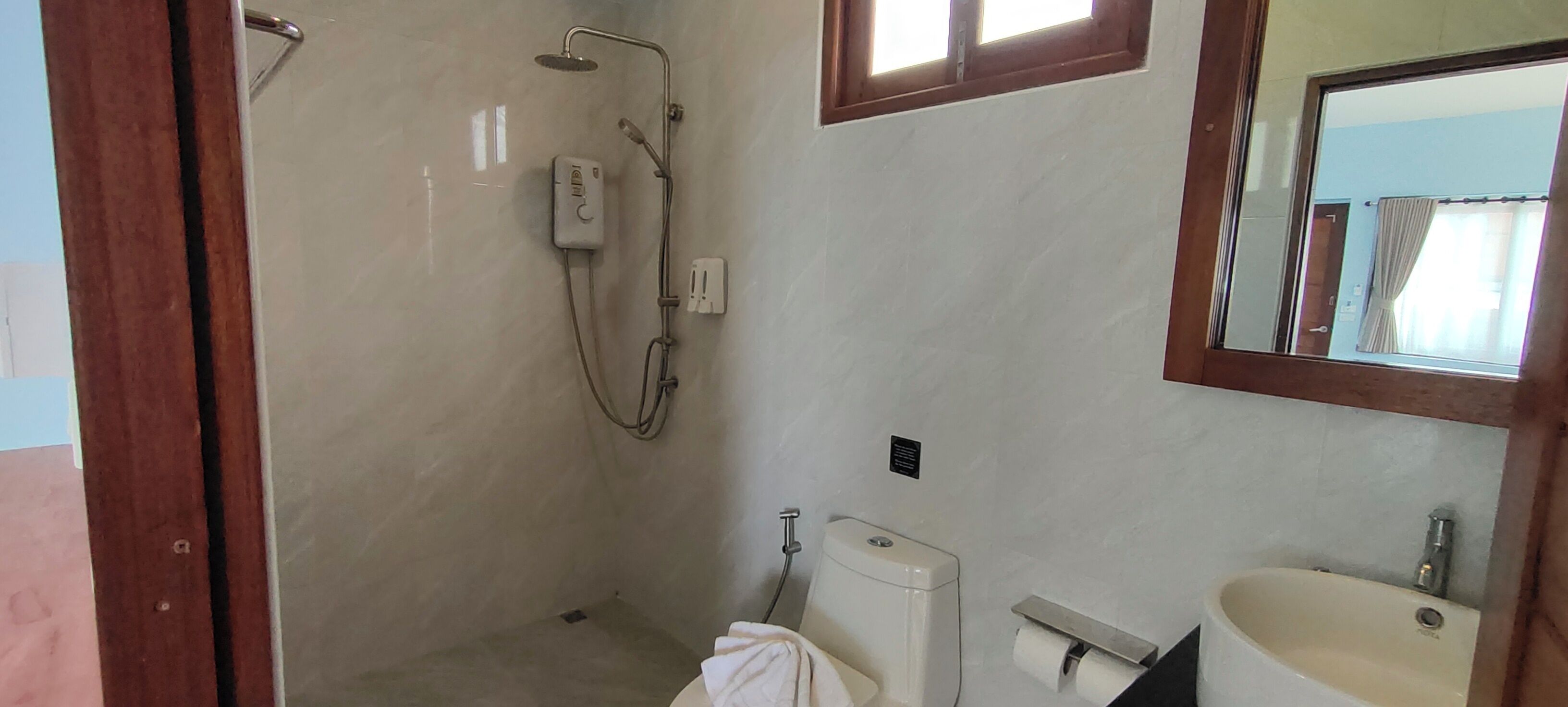 Un bagno con doccia, WC, lavandino e specchio.