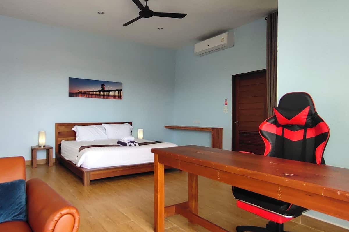 Habitación de hotel con cama, escritorio, silla e imagen colgada en la pared.