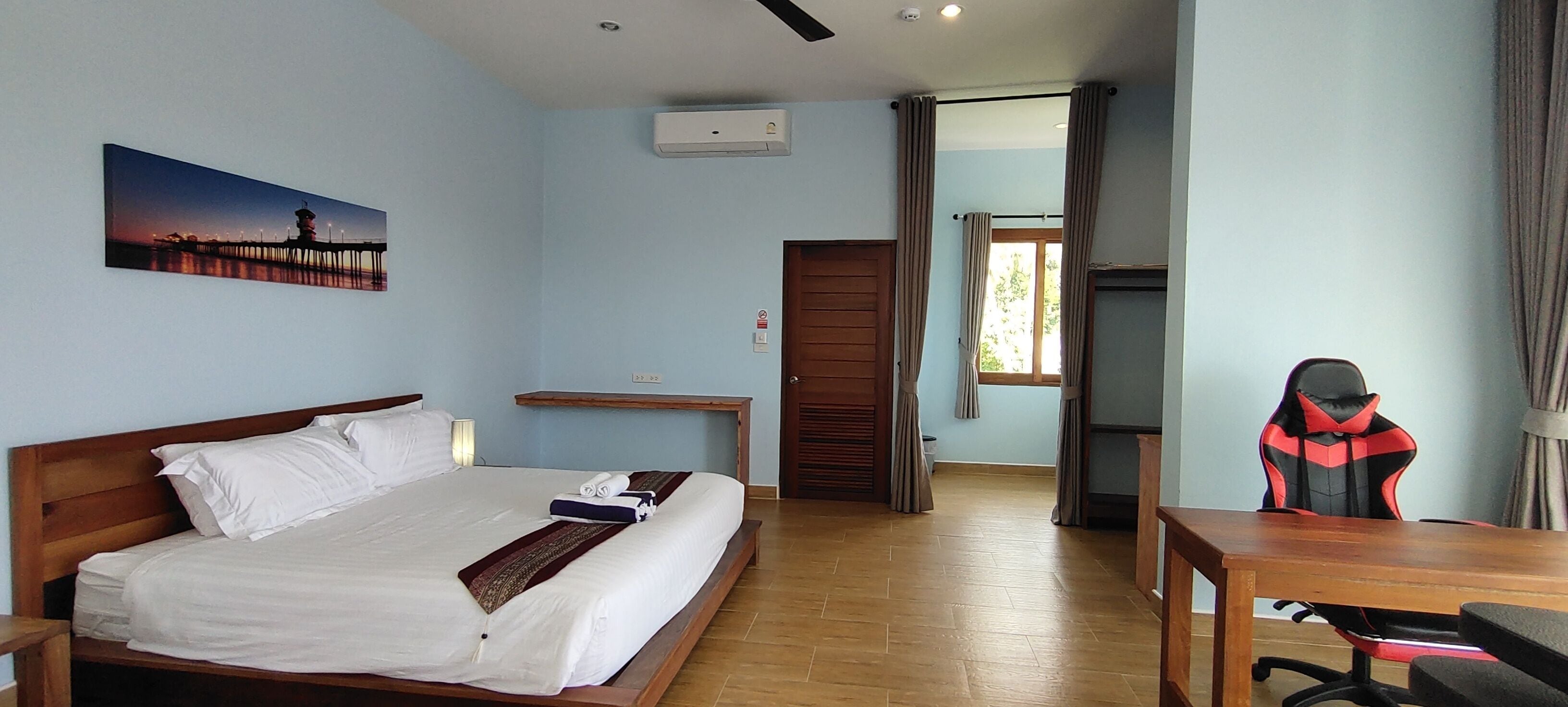 Una habitación de hotel con cama, escritorio, silla, ventana y un cuadro en la pared.