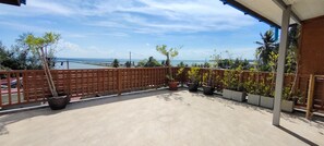 A balcony with potted plants, a view of the sea, and a wooden fence.