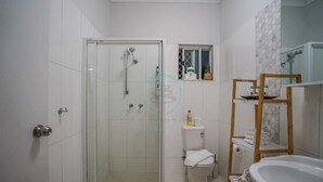 A modern bathroom with a glass-enclosed shower, a toilet, and a sink. - ZEN HIDEAWAY - Cozy 2BR Modern Unit (Alawa)