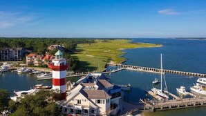 A coastal town with a lighthouse, marina, and buildings with visible balconies.
