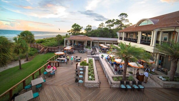 A resort with outdoor seating, a pool, and a view of the ocean.