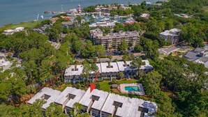 An aerial view of a coastal resort with multiple buildings, a marina, and a swimming pool.