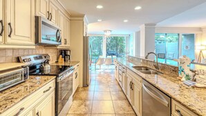 A kitchen with granite countertops, stainless steel appliances, and a view to a patio area.