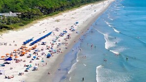 A beach with rows of umbrellas and people.