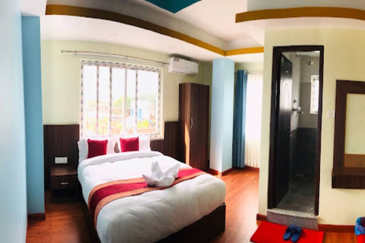 Ein Hotelzimmer mit Bett, Fernseher, Dusche und Blick ins Freie.