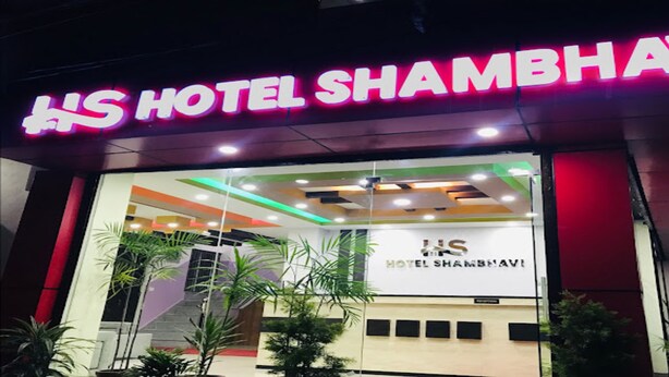 L’extérieur de l’hôtel Shambhavi se distingue par une enseigne au néon bien visible et une architecture moderne.