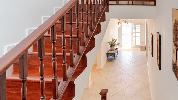 Eine Holztreppe mit Handlauf, die zu einer oberen Etage führt.