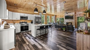 A spacious kitchen with wooden ceiling, white cabinets, and a large island. - Luxe Cabin|Indoor Pool~Game & Theater Rooms! (Sevierville)
