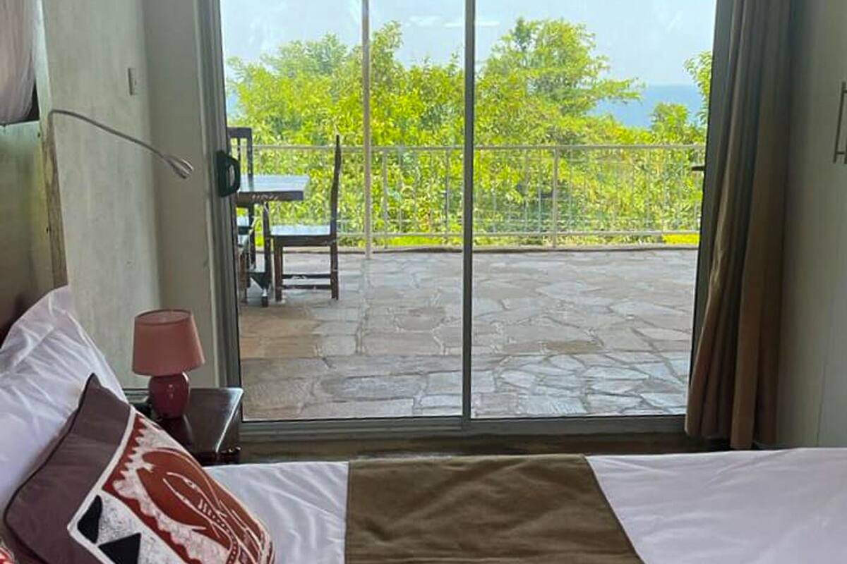 A bedroom with a bed, pillows, a lamp, and a view of a patio with a table and chairs.
