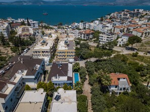 A coastal residential area with modern buildings, a visible swimming pool, and a clear view of the sea. - Jash Bedrooms (Milas)