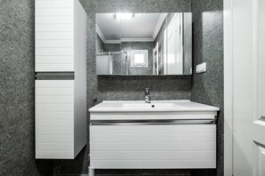 A modern bathroom with a white vanity, a large mirror, and a granite countertop. - Jash Bedrooms (Milas)