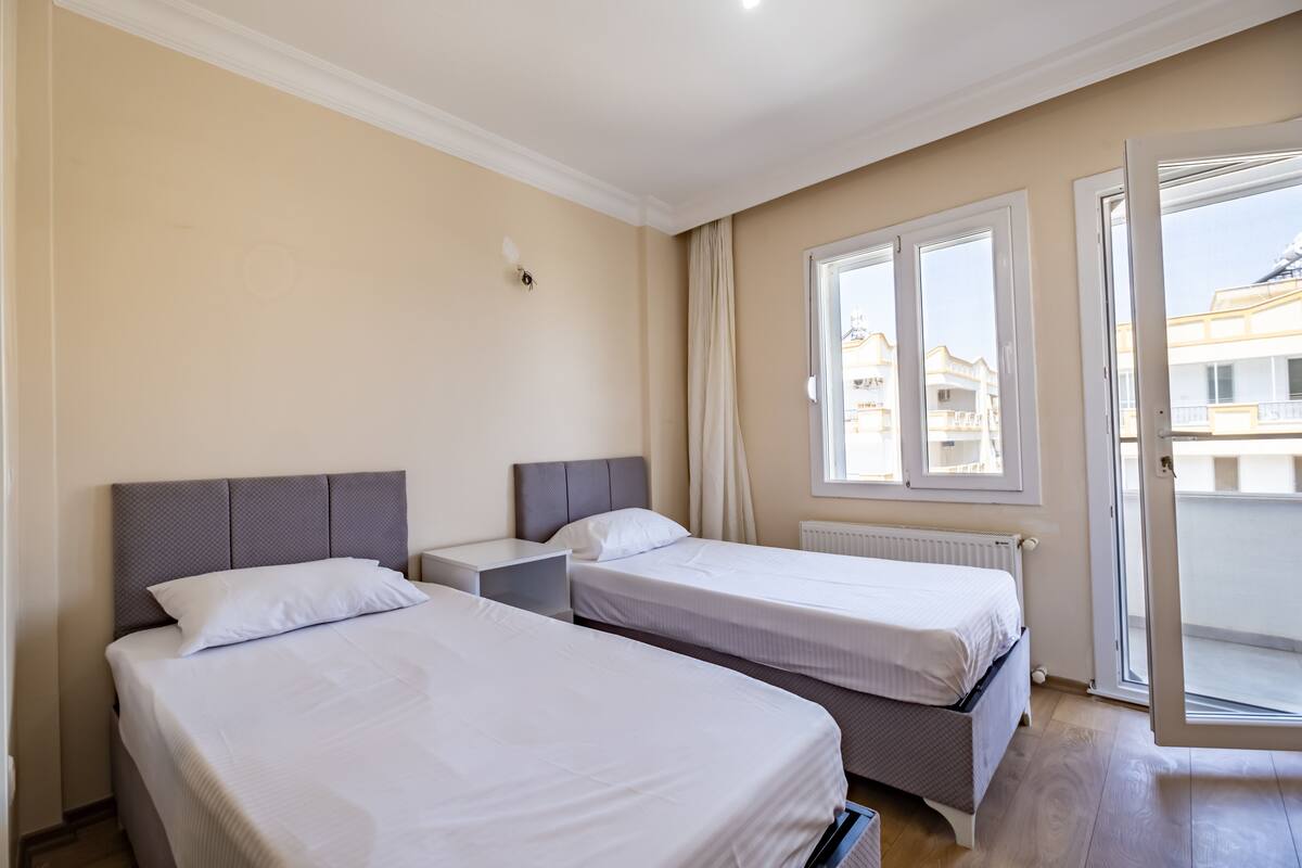 Ett hotellrum med två sängar, ett fönster och utsikt över byggnaderna utanför.