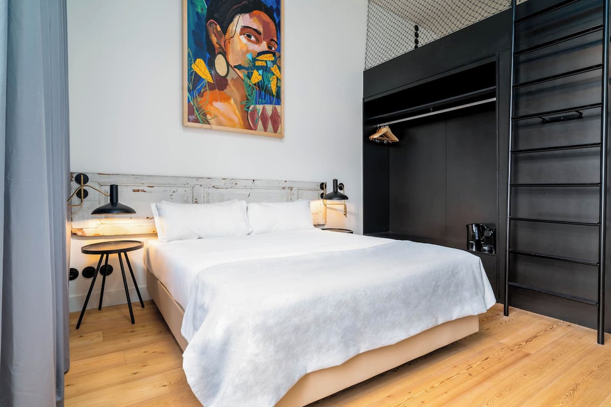 Un dormitorio moderno con una cama grande, mesitas de noche, un cuadro en la pared y un armario negro.