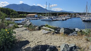 A marina with boats docked, a sandy foreground, and mountains in the background. - Villa Melody Calme DS Residence Securisee Avec Piscines Proche MER ET Montagne (Santa-Maria-Poggio)