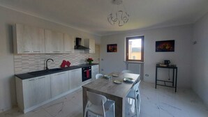A modern kitchen with a dining area, featuring a large island, white cabinets, and a black countertop. - Orchid Roero Sunsetfor couples families groups to visit Roero and Langhe (Govone)