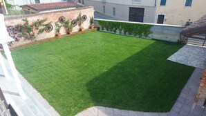 A well-maintained rooftop garden with a grassy area, brick walls, and potted plants. - Orchid Roero Sunsetfor couples families groups to visit Roero and Langhe (Govone)