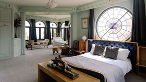 A spacious bedroom with a large bed, a desk, and a chair. - Christie Mansion - Luxury Cottages (Shanklin)