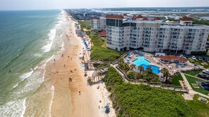 Vista aérea de un hotel costero con playa, piscina y varios edificios.